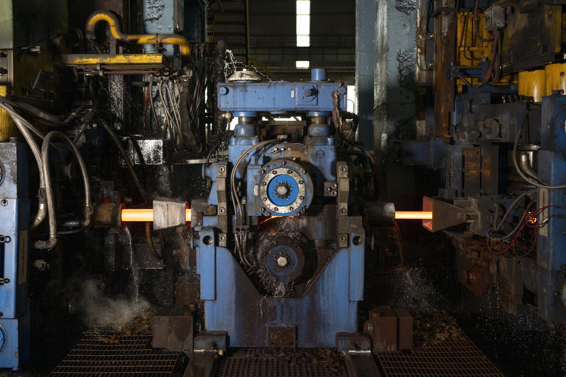 Red-hot steel bar passing through a rolling stand
